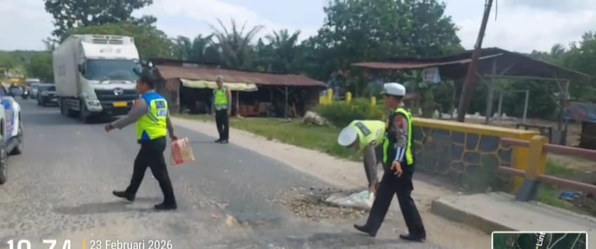 Personel Satlantas Polres Labusel menambal jalan berlubang di jalinsum tepatnya titi kembar. (KHAIRUDDIN/SUMUT POS)