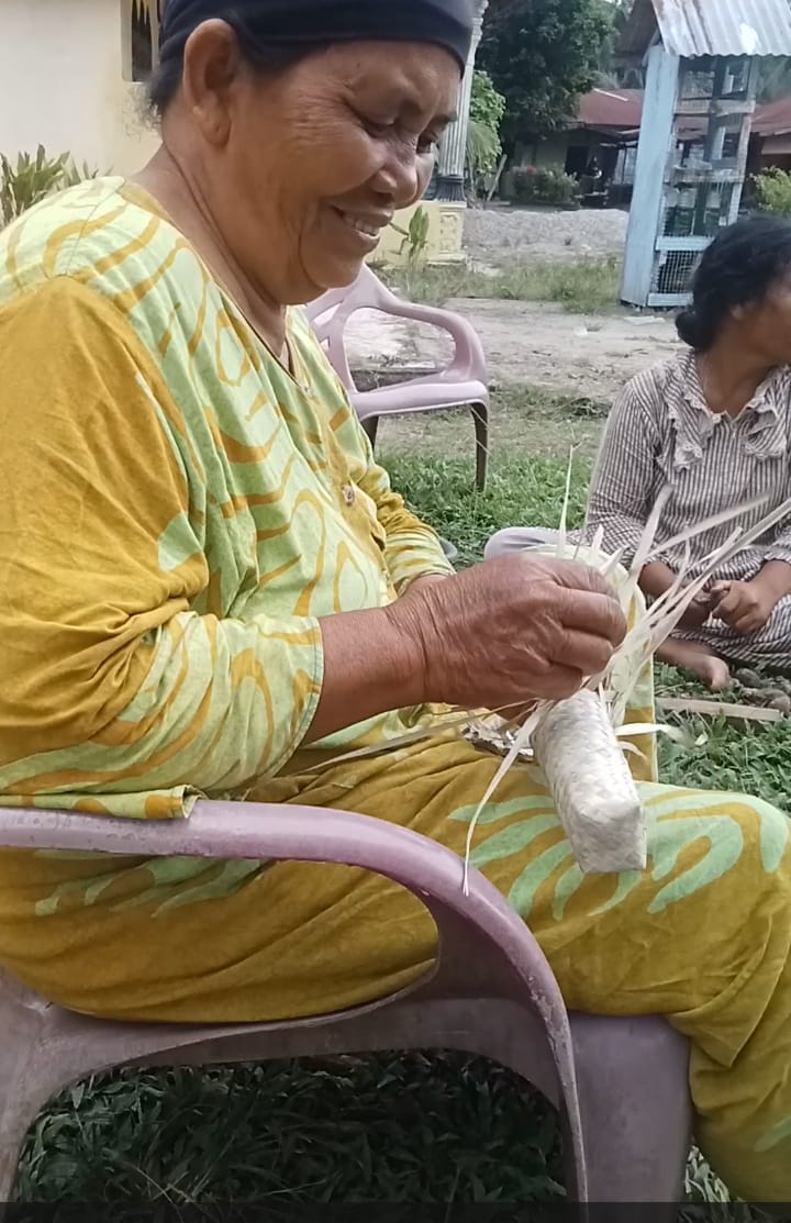 Seorang ibu rumah tangga sedang membayu (menyulam) bungkusan dodol yang saat ini permintaannya meningkat menjelang hari raya Idul Fitri.