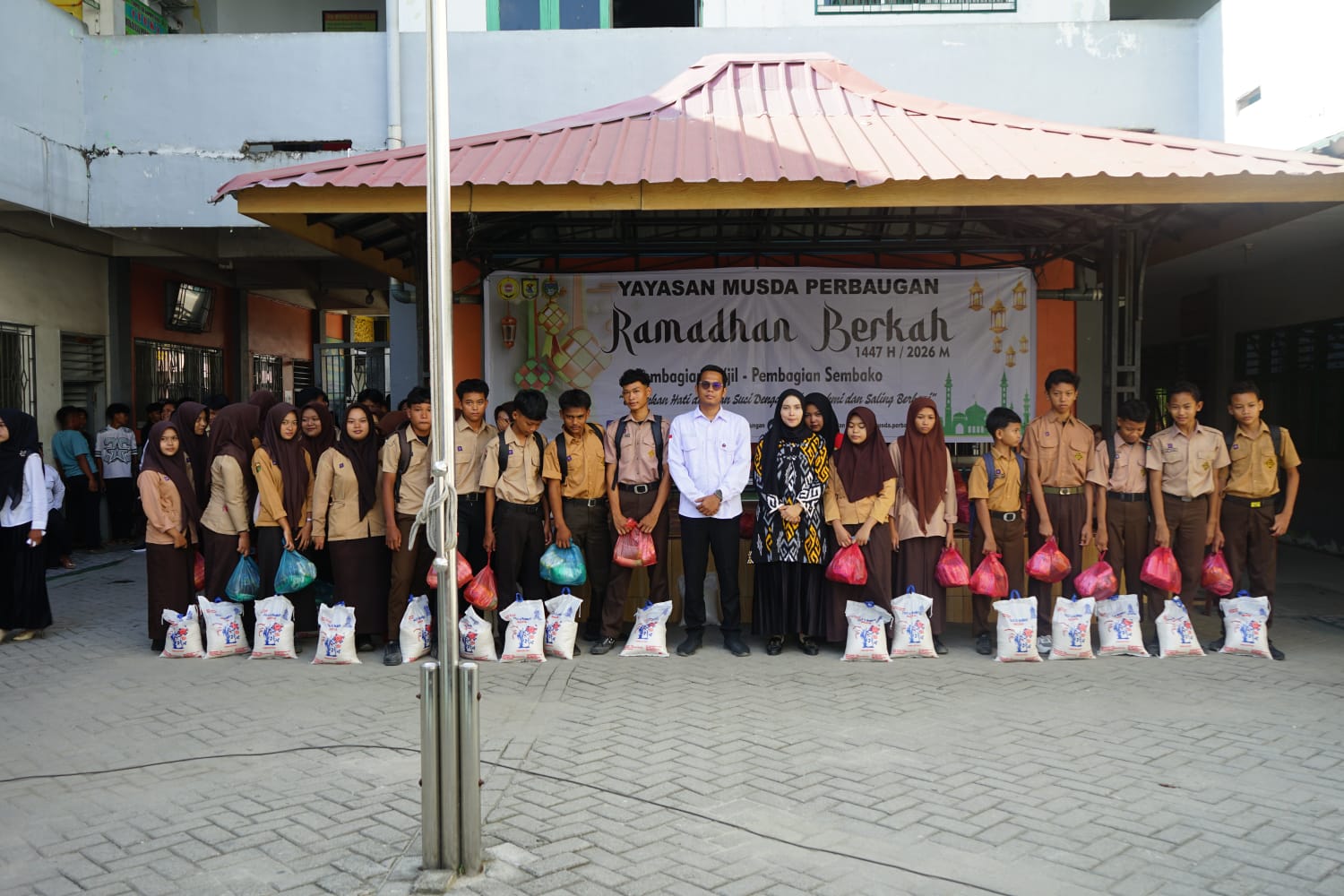 BERSAMA: Kepala SMK Musda Perbaungan, Aditya Utama, S.Kom foto bersama siswa/siswi seusai bagikan sembako. (Dok: Fadli/Sumut Pos) 