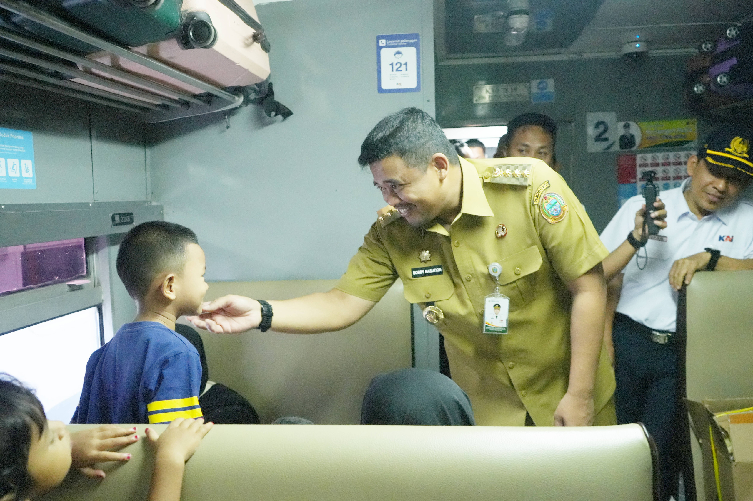 BERCANDA: Gubsu Bobby Nasution saat bercanda dengan anak yang akan mengikuti program mudik gratis melalui kereta api, Senin (16/3/2026). (Dok: istimewa)