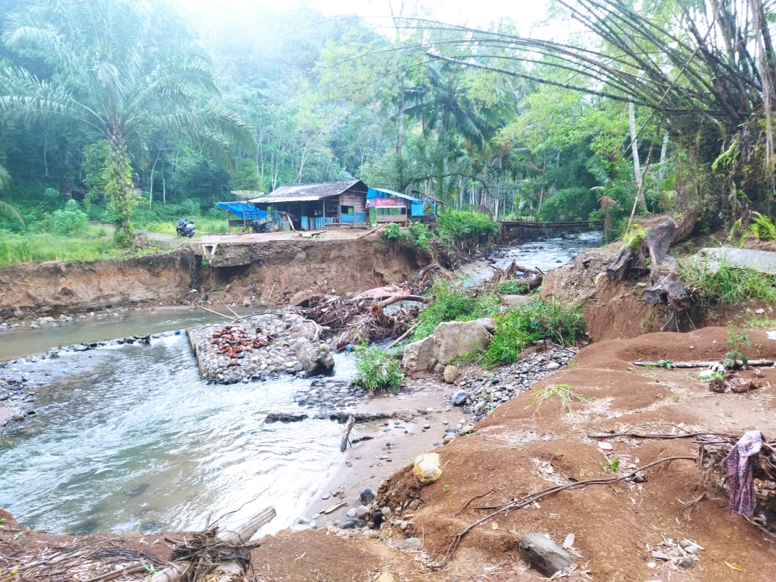 Badan jalan membentuk alur sungai baru dan tebing jalan amblas hingga irigasi kering akibat alur sungai yang pindah. (SUBANTA RAMPANG AYU/SUMUT POS)
