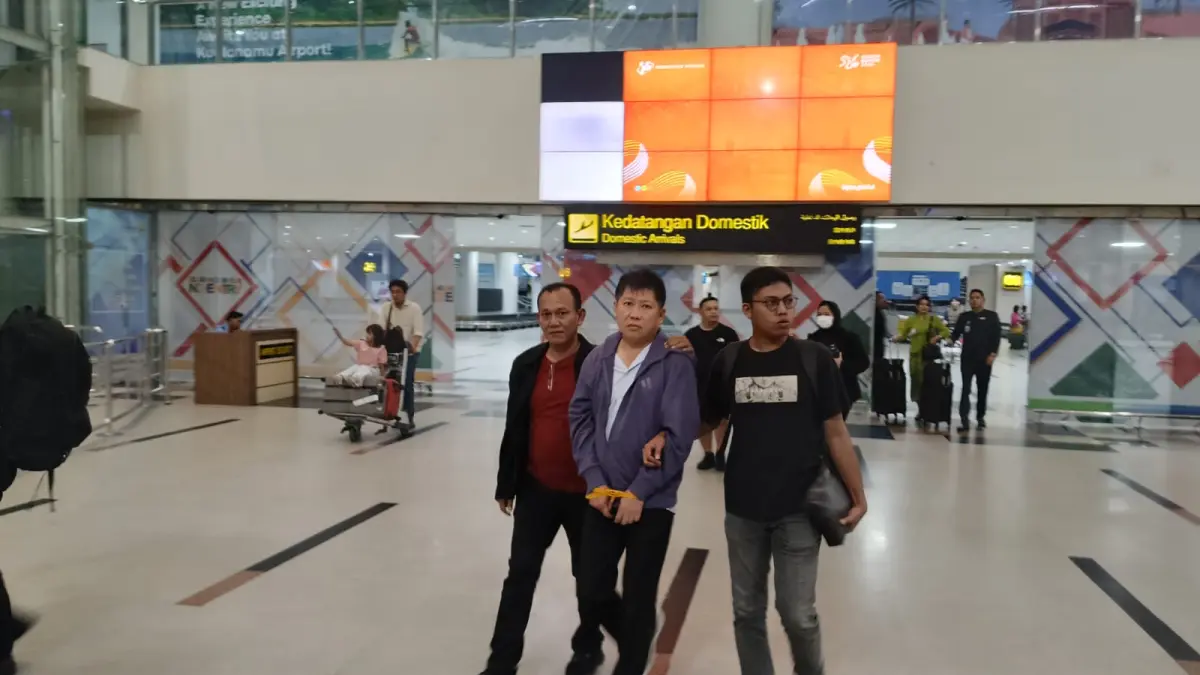 Personel  Poldasu mengiring tersangka saat tiba di terminal Bandara Kualanamu pada Selasa (14/4/2026) sekitar pukul 22.50 WIB dengan pesawat Citilink nomor penerbangan QG 882 dari Jakarta. (ISTIMEWA/SUMUT POS)