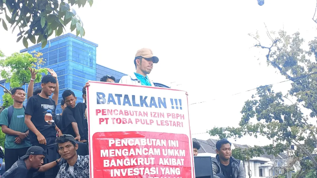 SPANDUK: Masa aksi membentangkan spanduk berisi pencabutan izin PBPH PT.TPL mengancam UMKM dan investasi yang sedang berjalan, yang ditunjukan didepan Kantor Gubernur Sumatera Utara, Jumat (18/4/2026). (Dok: Ihsan Syahreza/ Sumut Pos)