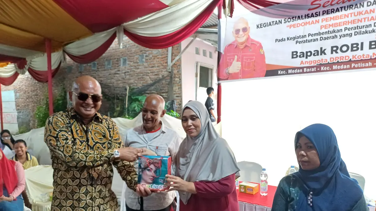CENDERAMATA: Ketua Fraksi PDI Perjuangan DPRD Kota Medan, Robi Barus  memberikan cenderamata kepada warga saat menggelar Sosialisasi Perda Kota Medan No.9 Tahun 2017 di Kecamatan Medan Barat, Minggu (19/4/2026) sore. (Dok: Markus Pasaribu/Sumut Pos) 