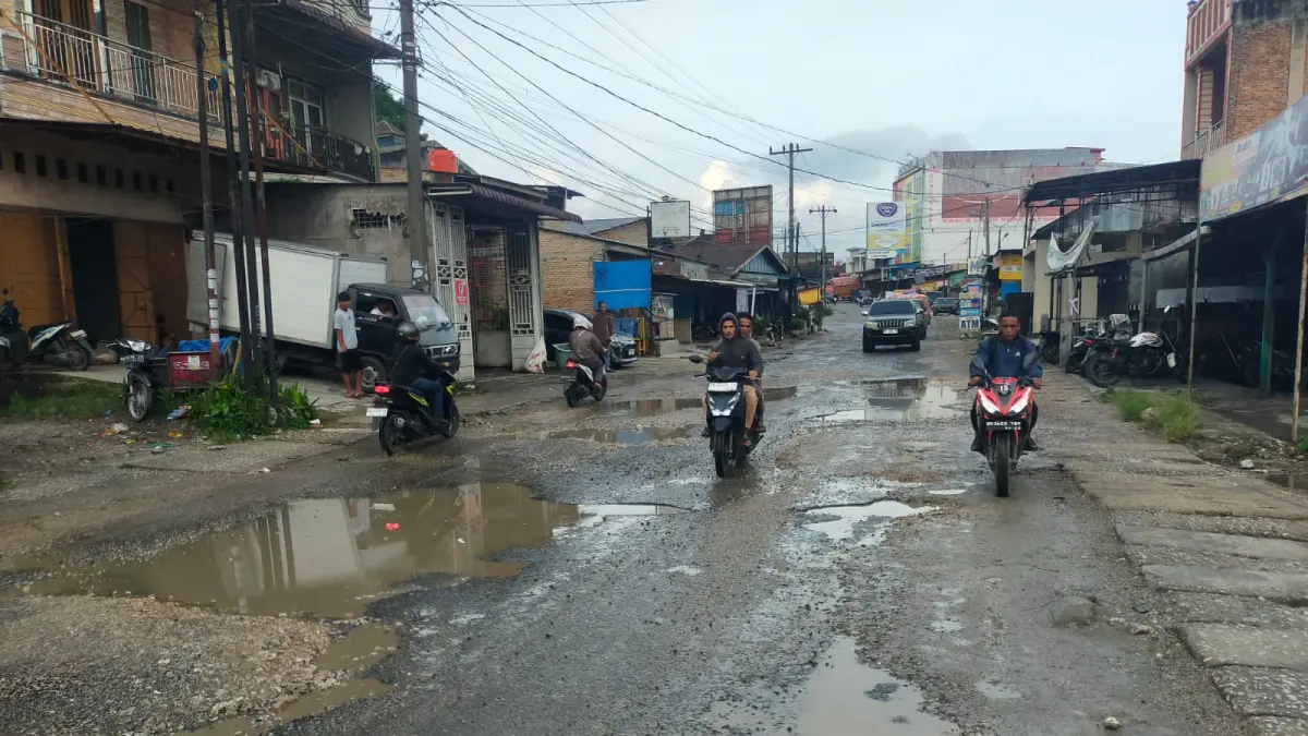 BERKUBANG:  Pengendara roda dua dan empat  melintas dari jalan Pakpak Sidikalang yang kondisinya rusak berat dan berkubang, Senin ((27/4/2026). (RUDY SITANGGANG/SUMUT POS)