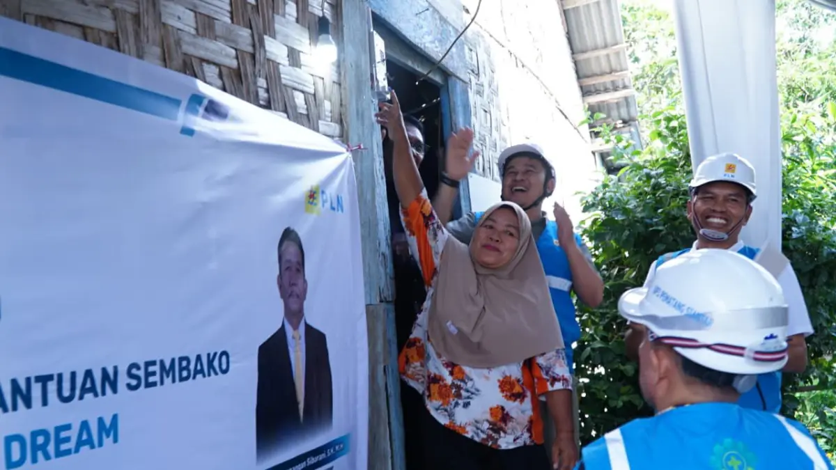 Senyum bahagia bu Atik saat menyalakan langsung listrik di rumahnya. (Istimewa/Sumut Pos)