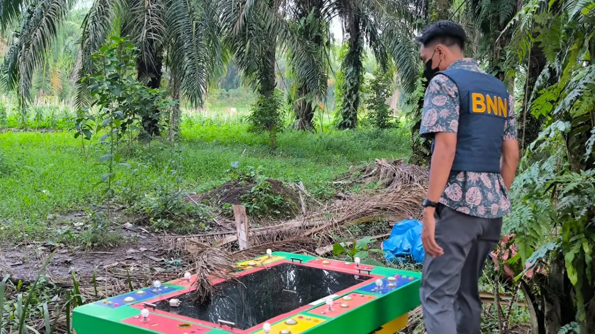 SEMBUNYI: Petugas BNNK Binjai saat menemukan mesin tembak ikan disembunyikan di balik sawit dan ditutupi terpal. (Dok: Teddy Akbari/Sumut Pos)