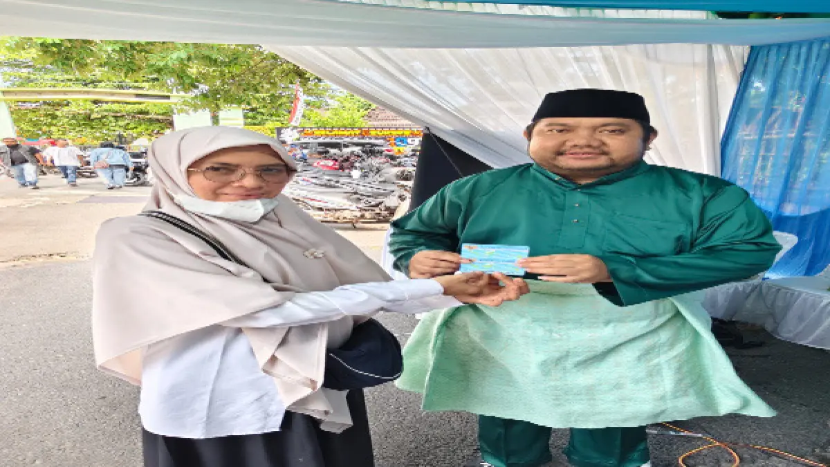 Plt Kepala Dinas Kependudukan dan Pencatatan Sipil (Disdukcapil) Kota Tebing Tinggi, Ramahda Barkah Pulungan, menyerahkan Kartu Tanda Penduduk Elektronik,kepada warga saat pelayanan administrasi kependudukan dalam rangka peringatan HUT ke-109 Kota Tebing Tinggi di halaman Balai Kota, Rabu (1/7/2026). (Azan Purba/Sumut Pos)
