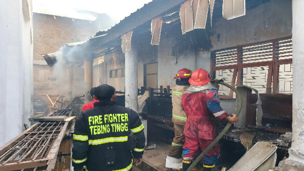 Petugas Dinas Pemadam Kebakaran (Damkar) Kota Tebingtinggi berupaya memadamkan sisa kobaran api di bangunan SMP Negeri 9 Tebingtinggi, Jalan Pusara Pejuang, Kelurahan Rambung, Kecamatan Tebingtinggi Kota, Selasa (28/7/2026). (Azan Purba / Sumut Pos)