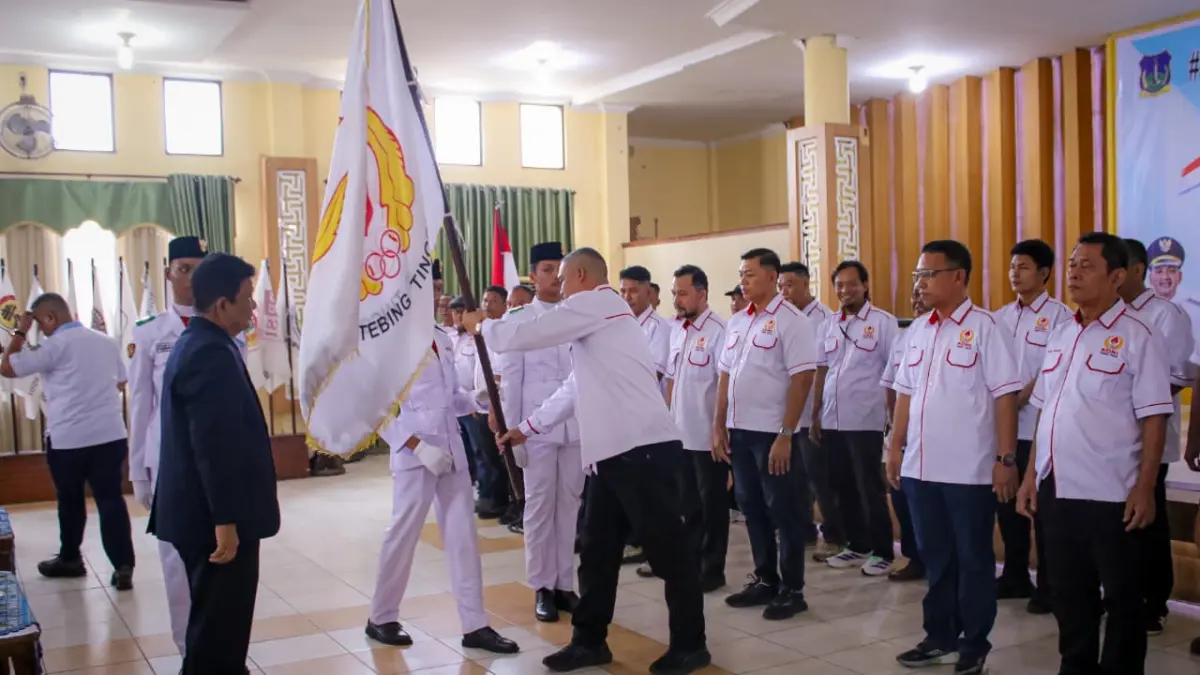 Ketua Umum KONI Sumut Kolonel TNI (Purn) Hatunggal Siregar menyerahkan bendera pataka kepada Ketua KONI Kota Tebing Tinggi Aulia Pitra dalam prosesi pelantikan Pengurus KONI Tebingtinggi masa bakti 2026–2030 di Gedung Hj Sawiyah, Kamis (17/9/2026). (Azan/ Purba Sumut Pos)