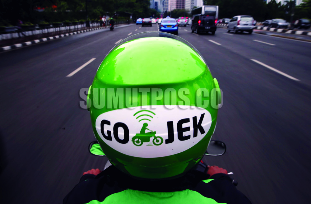 Foto: REUTERS/Beawiharta  Seorang pengemudi Gojek mengendarai sepeda motornya melewati area bisnis di Jakarta, 9 Juni 2015 lalu. Tarif atas bawah angkutan online diberlakukan per 1 Juli 2017.