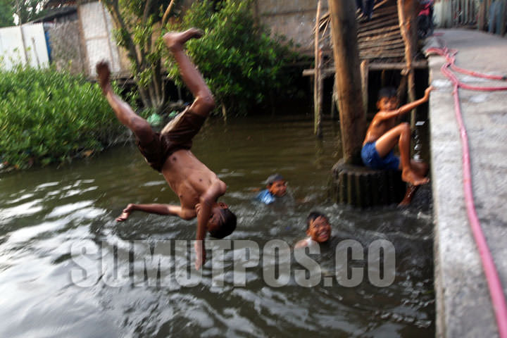 File/SUMUT POS Seorang bocah melompat ke air dipinggiran kampung mereka di Jalan Baung Pajak Baru Kelurahan Belawan Bahagia, Kecamatan Medan belawan, belum lama ini.