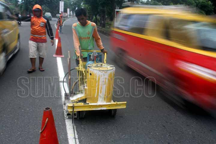 SUTAN SIREGAR/SUMUT POS MENGECAT_Seorang pekerja mengecat batas jalan di Jalan Yos Sudarso Medan, Kamis (10/8) Pengerjaan tersebut guna memberikan rasa nyaman kepada pengendara yang melintas di jalan tersebut.
