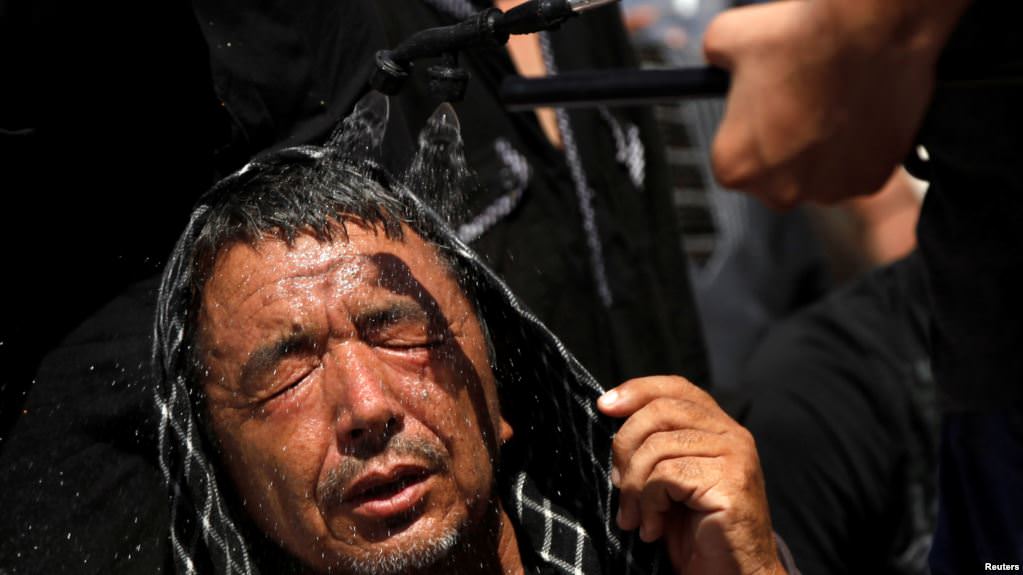 Foto: VOA  Seorang pria sedang menerima semprotan air dingin untuk menghindari panas saat mengikuti prosesi Syiah Youm Ali di Karachi, Pakistan, 27 Juni 2016.