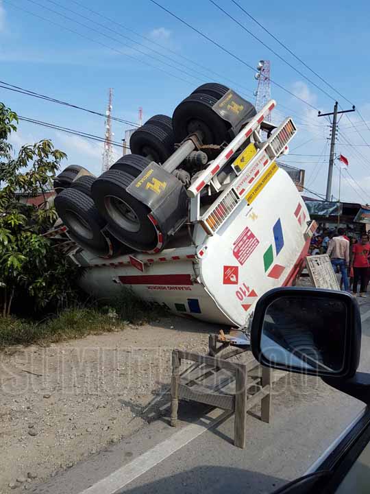 Foto: BAMBANG/SUMUT POS TERBALIK: Truk tangki Pertamina pengangkut bahan bakar minyak (BBM) jenis Pertalite terbalik di Pasar IV Tanjung Beringin Kecamatan Hinai Kabupaten Langkat, Minggu (28/8).