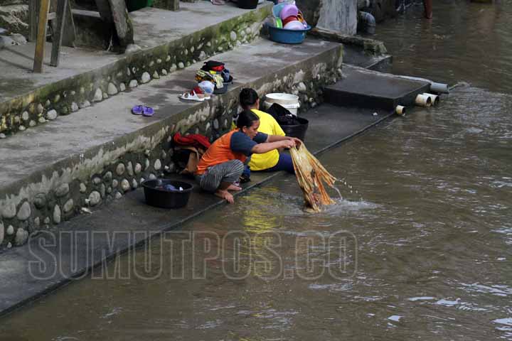 SUTAN SIREGAR/SUMU POS Seorang wanita terlihat sedang mencuci pakaian di pinggiran aliran sungai deli Jalan Mangkubumi Medan, Minggu (24/7) Angka kemiskinan di kota medan di tahun 2016 meningkat.