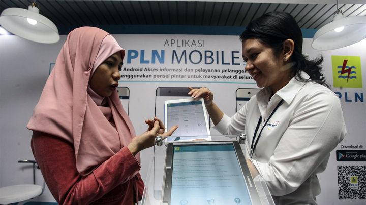 Seorang wanita menunjukkan Aplikasi PLN Mobile.