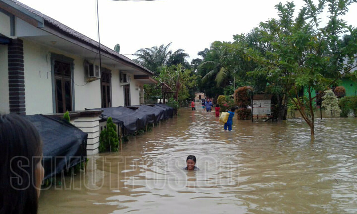 Foto: BAMBANG/SUMUT POS TERENDAM: Seorang anak perempuan terendam banjir saat melintasi jalan yang tak jauh dari rumahnya di Kecamatan Besitang, Rabu (11/10).