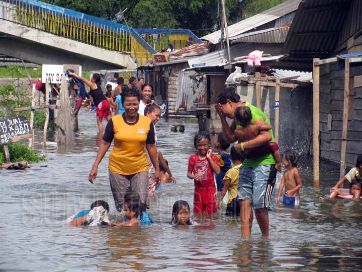 Foto: Fachril/Sumut Pos Sejumlah warga dan anak-anak di Kecamatan Medan Belawan tampak bermain di genangan air akibat banjir rob.