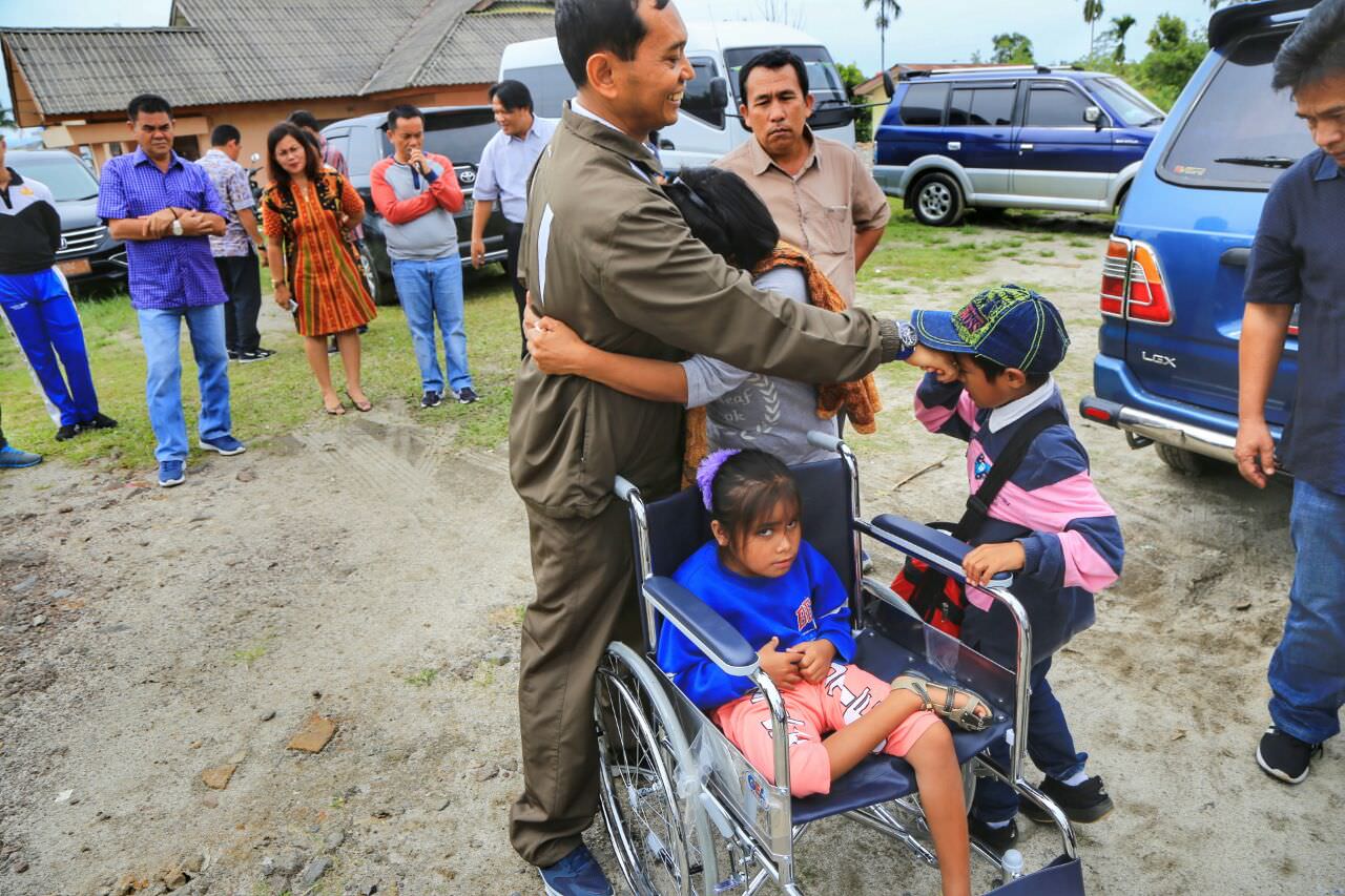 Foto: Tonggo/SMG Bupati Simalungun JR Saragih dipeluk a ak-anak, usia menyerahkan kursi roda kepada penyandang disabilitas di Pematang Raya, Kabupaten Simalungun, Sumatera Utara, Jumat (27/10/2017).