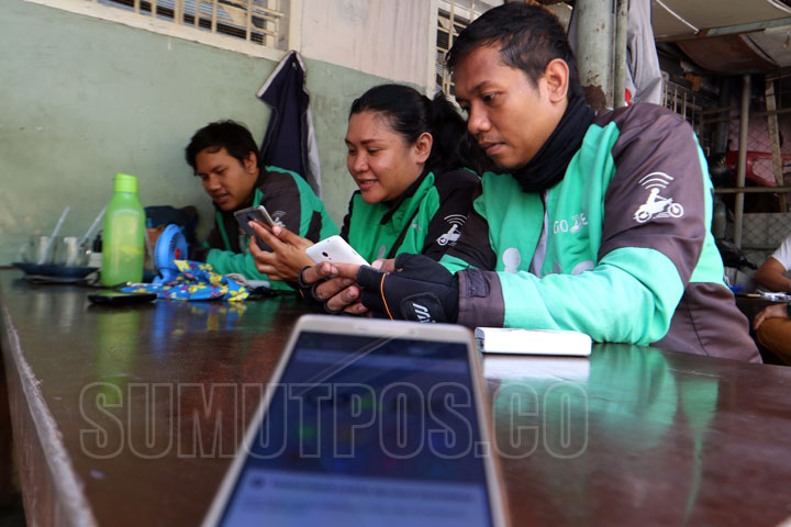 SUTAN SIREGAR/SIREGAR DRIVER GOJEK_Driver Go-jek sedang membeli pesanan pelanggan aplikasi online di rumah makan Jalan Sumatera Medan, Rabu (2/8) Meskipun dinas perhubungan sumatera utara sudah melarang izin operasi angkutan berbasis online, driver aplika