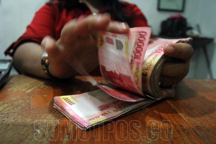 Sutan siregar /SUMUT POS - Teller menghitung lembaran uang rupiah di salah satu tempat penukaran mata uang asing (money changer) Jalan Juanda Medan, Rabu (7/10). Rupiah kembali menguat terhadap dolar Amerika Serikat, hingga sore ini, dolar AS menyentuh le