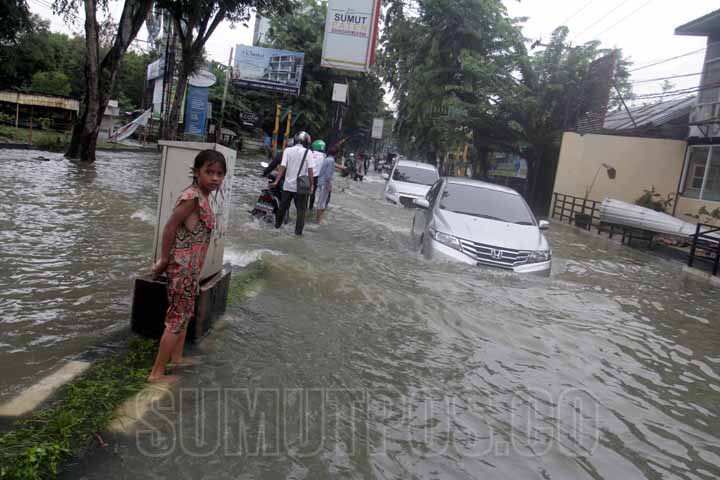 SUTAN SIREGAR/SUMUT POS BANJIR_Warga menggunakan kendaraan menembus banjir yang merendam Jalan dr Mansyur, Senin (9/7). Hujan deras yang mengguyur Kota Medan pada Minggu (8/7) malam ditambah meluapnya aliran anak Sungai Batuan menyebabkan puluhan rumah da