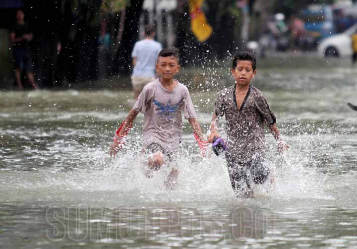 SUTAN SIREGAR/SUMUT POS BANJIR_Warga menggunakan kendaraan menembus banjir yang merendam Jalan dr Mansyur, Senin (9/7). Hujan deras yang mengguyur Kota Medan pada Minggu (8/7) malam ditambah meluapnya aliran anak Sungai Batuan menyebabkan puluhan rumah da