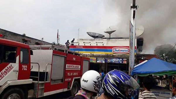 bambang/sumut pos PEMADAMAN: Petugas Kebakaran dan masyarakat saat memadamkan api yang melalap lantai II Indomaret Gebang.