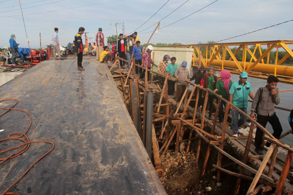 SUTAN SIREGAR/SUMUT POS            JEMBATAN: Warga melintasi jembatan darurat di Jalan Sicanang Medan Labuhan, Rabu (31/10). Jembatan Titi II yang dibangun PT Jaya Suskes Prima, rubuh sebelum rampung.