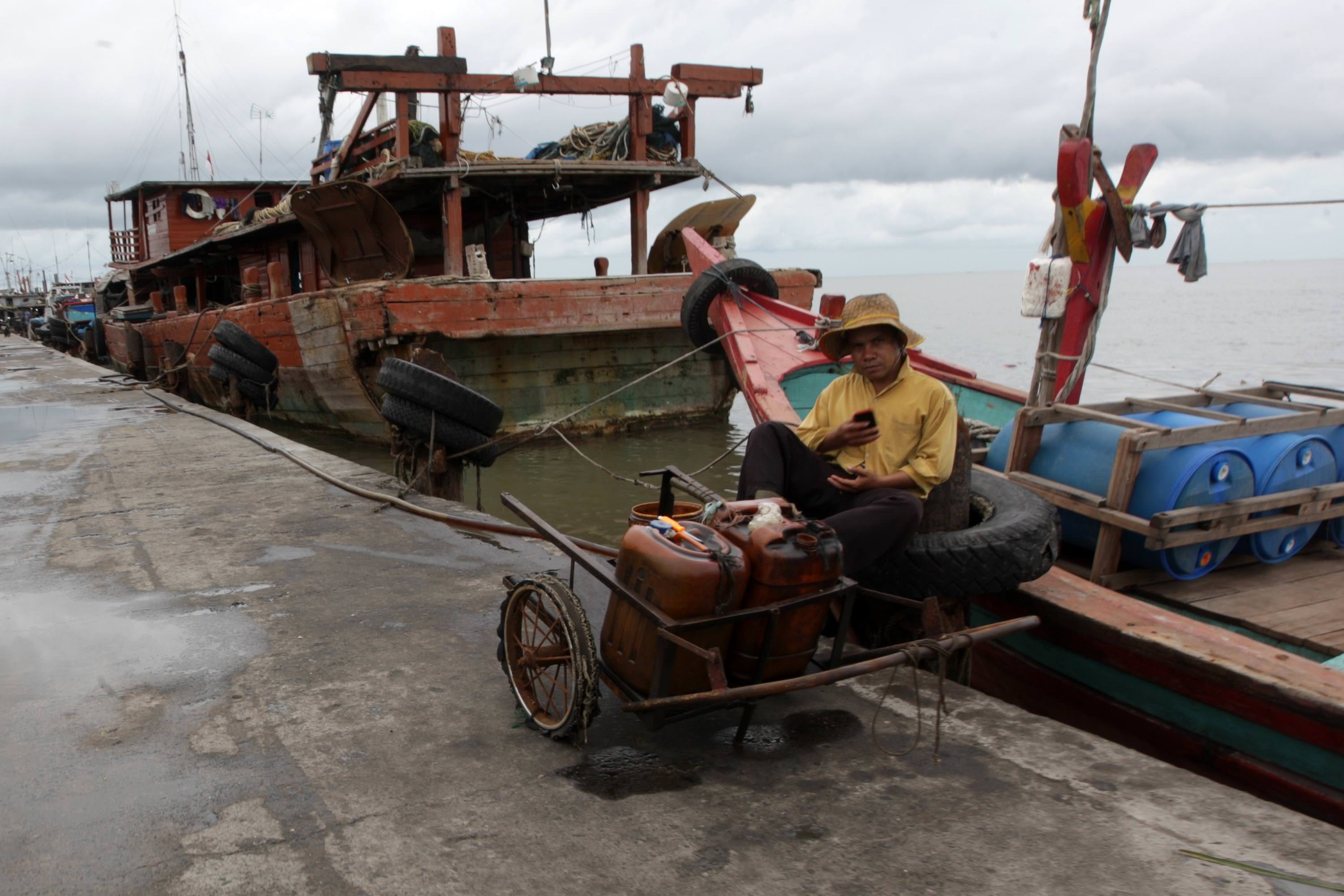 FILE/SUMUT POS Seorang nelayan menampung minyak yang tumpah saat perahu nelayan melakukan pengisian bahan bakar di Dermaga Pelabuhan Perikanan Samudera Belawan (DPPSB) Belawan, belum lama ini.