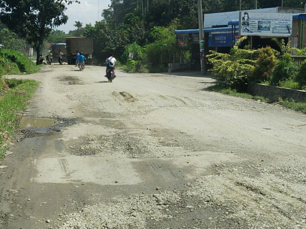 teddy akbari/sumut pos RUSAK: Pengendara sepeda motor melintasi ruas jalan menuju kawasan wisata Bukit Lawang, Bahorok, yang mengalami kerusakan cukup parah, belum lama ini.