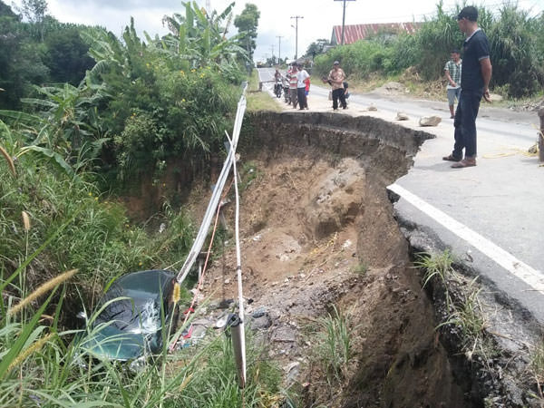 RUDY SITANGGANG/SUMUT POS TERJUN BEBAS. Mobil Avanza terjun bebas ke jurang di lintasan jalan nasional Sidikalang-Dolok Sanggul yang amblas.