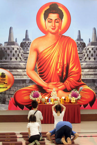 SUTAN SIREGAR/SUMUT POS WAISAK: Umat Buddha saat sembahyang menyambut Hari Waisak di Vihara Borobudur Jalan Imam Bonjol Medan, Minggu (19/5). Foto kanan, Seorang wanita mengikuti prosesi pemandian Rupang Buddha.  Perayaan Waisak 2563 B.E/2019 tersebut dil