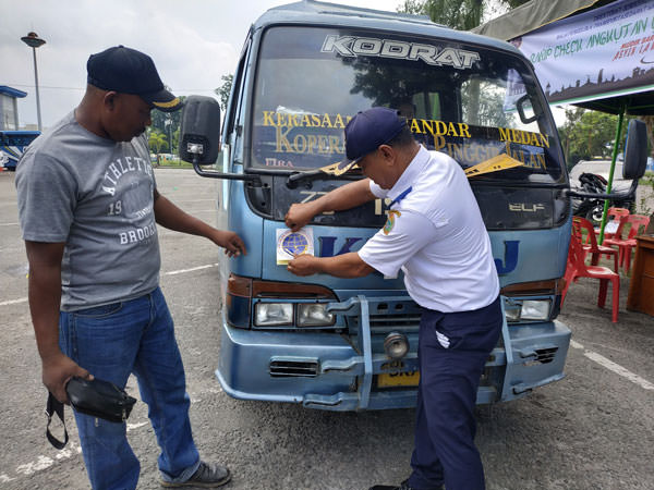 Petugas memasang stiker pada kenderaan yang sudah lulus pemeriksaan.