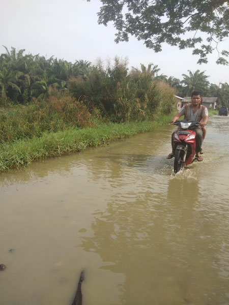 fachril/sumut pos BANJIR: Pengendara motor melintasi genangan air di Jalan Bakti Abri, Martubung.