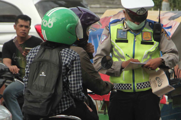 SUTAN SIREGAR/SUMUT POS             TILANG: Seorang petugas kepolisian menilang kendaraan roda 2 saat Operasi patuh toba 2019 di Jalan Bukit Barisan Medan, Kamis (29/8). Operasi Patuh Toba 2019  dilaksanakan selama 14 hari ke depan.