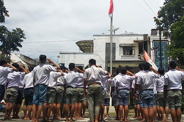HORMAT BENDERA: Seratusan pelajar di Siantar yang bolos saat jam pelajaran terjaring razia petugas Satuan Polisi Pamong Praja, Senin (26/8) pagi. Mereka diminta menghormat bendera sebagai hukuman.