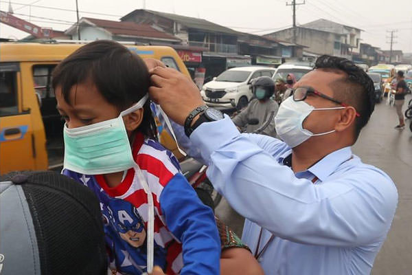 istimewa/sumut pos MASKER: Pegawai UPK Belawan memakaikan masker pada bocah yang berada di boncengan sepeda motor.