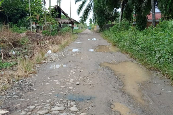BERLUBANG: Kondisi Jalan Perjuangan , desa Pelawi Selatan yang berlubang dan saluran air tidak berfungsi karena tersumbat. ILYAS EFFENDY/ SUMUT POS