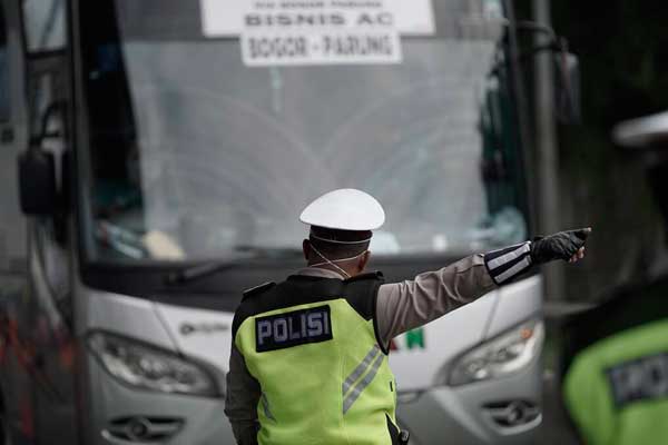 PUTAR BALIK Personel Polda Metro Jaya mengalihkan bus keluar tol Cikarang Barat di jalan tol Cikampek, Bekasi, Jawa Barat, Jumat (24/4). Buntut larangan mudik yang ditetapkan pemerintah, ribuan kendaraan disuruh memutar balik kembali ke asal. Poldasu juga