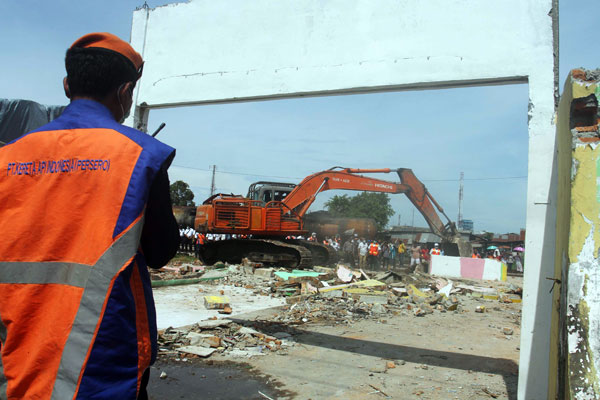 ROBOHKAN: Alat berat saat merobohkan bangunan yang berdiri di kawasan pinggiran rel Jalan Stasiun Kereta Api lama, Belawan, beberapa waktu lalu.