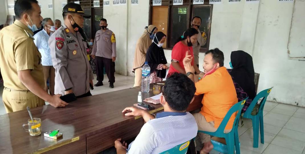 PANTAU: Kapolsek Sipispis AKP Syaipullah didampingi Camat Sipispis Rico Ebtian memantau penyaluran BST di Balai Desa Sipispis, Selasa (12/1).sopian/sumut pos.