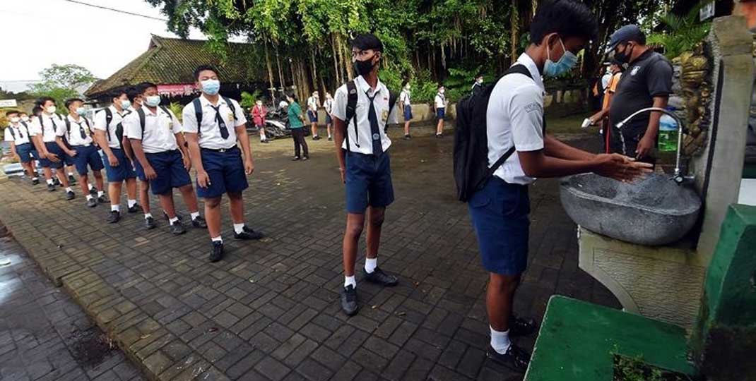 CUCI TANGAN: Siswa mencuci tangan saat akan memasuki area sekolah dalam PTM di SMP Negeri Hindu 2 Sukawati, Gianyar, Bali, Selasa (23/3). Pemkab Gianyar membuka PTM bagi siswa SD dan SMP dengan menerapkan prokes, mengatur jumlah siswa, serta membagi waktu