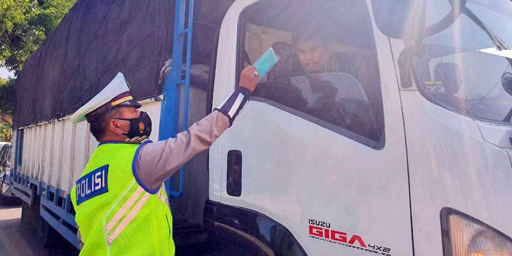 SOSIALISASI: Petugas kepolisian melakukan sosialisasi Prokes Covid-19 dengan memberikan masker kepada pengemudi truk. sopian/sumut pos.