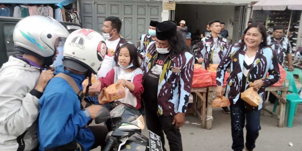 BAGIKAN: Ketua DPD IPK Karo memberikan takjil pada pengendara yang melintas. SOLIDEO/SUMUT POS.