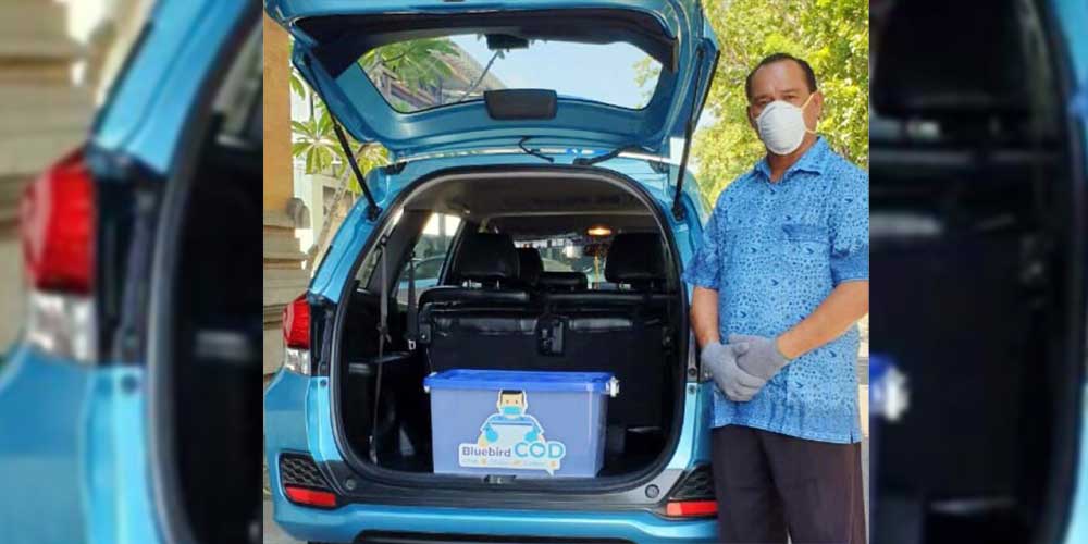 ANGKUT: Pengemudi BlueBird berdiri di sebelah mobil dan logistik.
