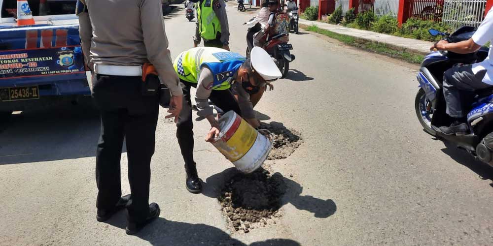 TAMBAL JALAN: Peduli keselamatan lalulintas, Personel Satuan Lantas Polres Nias tambal jalan berlubang di seputaran Jalan Karet, Kota Gunungsitoli, Selasa (8/3).adi laoli/sumut pos.