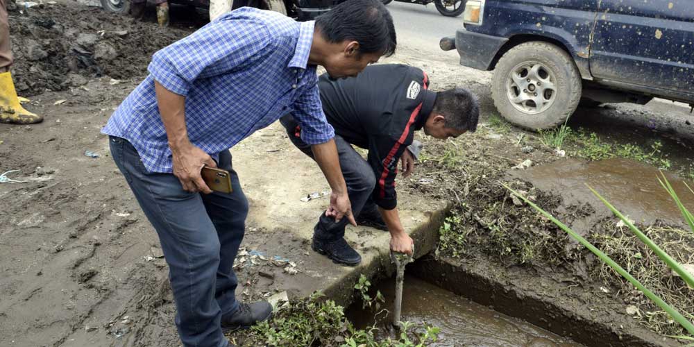 TINJAU: Wakil Bupati Karo Theopilus Ginting saat meninjau saluran drainase yang sumbat di Simpang Ujungaji, Jumat (22/4).