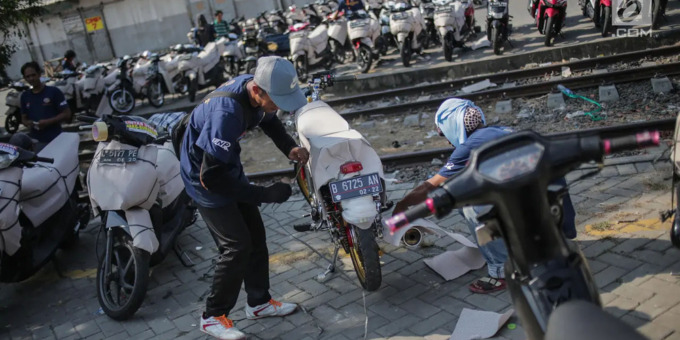 BUNGKUS MOTOR: Seorang pekerja membungkus sepeda motor pemudik sebelum dikirim dengan kereta api di Stasiun Jakarta Gudang. Pada mudik tahun ini, Kemenhub akan menyediakan gerbong gratis untuk mengangkut motor para pemudik.istimewa/sumutpos.